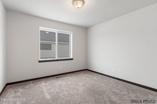 carpeted spare room with visible vents and baseboards