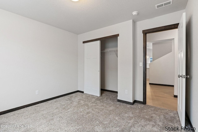 unfurnished bedroom featuring baseboards, a closet, visible vents, and carpet flooring