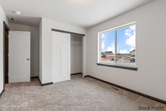 unfurnished bedroom with a closet, baseboards, visible vents, and carpet flooring