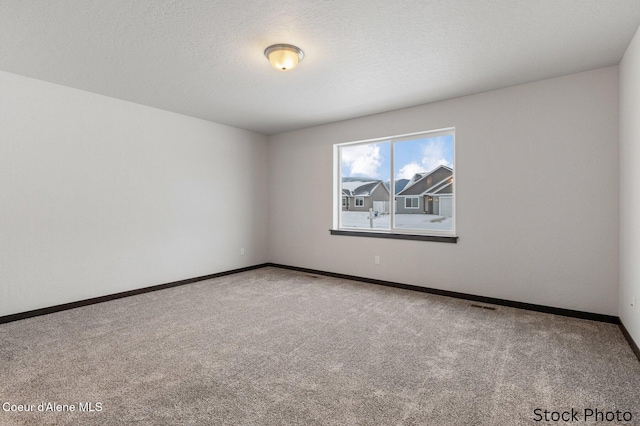 spare room with carpet, visible vents, a textured ceiling, and baseboards