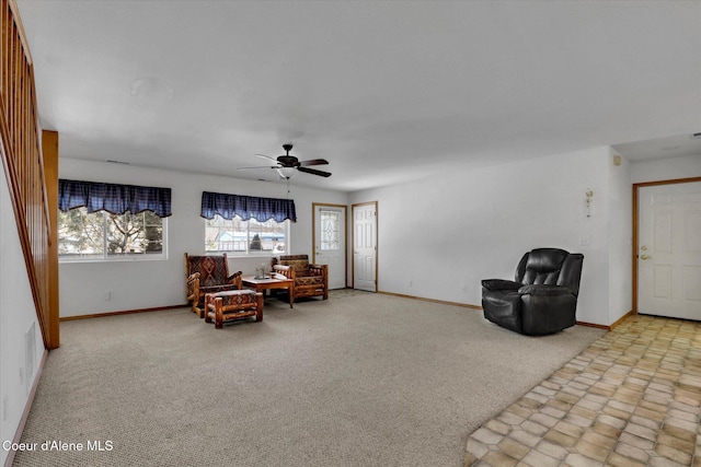 living area featuring carpet floors, baseboards, and a ceiling fan