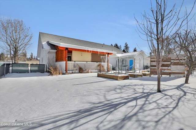 snow covered rear of property with fence and a porch