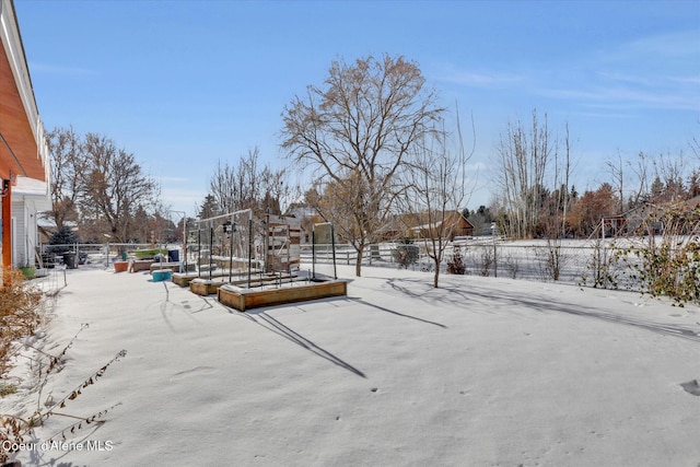 snowy yard with a garden and fence