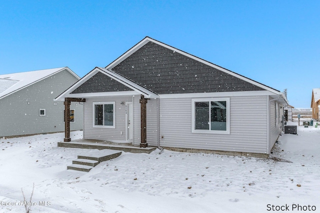 snow covered house featuring central air condition unit