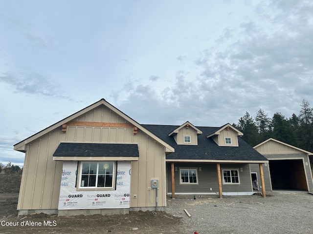 view of front of home with an outbuilding, roof with shingles, board and batten siding, and a garage