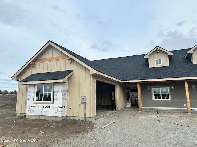 view of front facade with an attached garage, a shingled roof, and board and batten siding