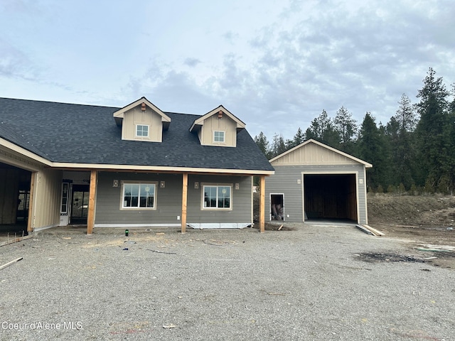 view of front of house featuring a shingled roof, driveway, a detached garage, and an outdoor structure