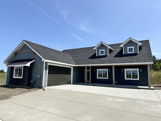 4550 E Savea Ln, Post Falls, ID 83854 - view of front of home with board and batten siding, an attached garage, driveway, and covered porch