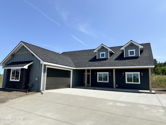 4550 E Savea Ln, Post Falls, ID 83854 - view of front of property with board and batten siding, an attached garage, concrete driveway, and covered porch