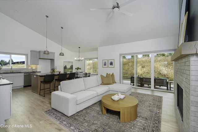 4550 E Savea Ln, Post Falls, ID 83854 - living room with high vaulted ceiling, a brick fireplace, a ceiling fan, light wood finished floors, and a chandelier