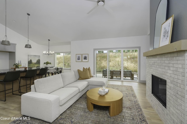 4550 E Savea Ln, Post Falls, ID 83854 - living room featuring vaulted ceiling, light wood finished floors, ceiling fan, a brick fireplace, and a chandelier
