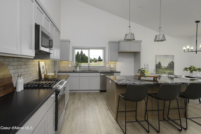 4550 E Savea Ln, Post Falls, ID 83854 - kitchen featuring appliances with stainless steel finishes, light wood finished floors, decorative backsplash, a breakfast bar area, and a chandelier