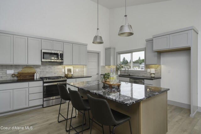 4550 E Savea Ln, Post Falls, ID 83854 - kitchen with stainless steel appliances, gray cabinetry, dark stone counters, a towering ceiling, and decorative backsplash