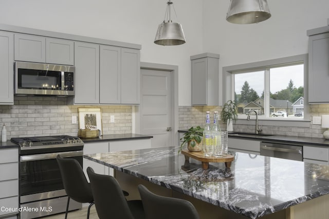 4550 E Savea Ln, Post Falls, ID 83854 - kitchen featuring stainless steel appliances, dark stone countertops, gray cabinets, backsplash, and a kitchen island