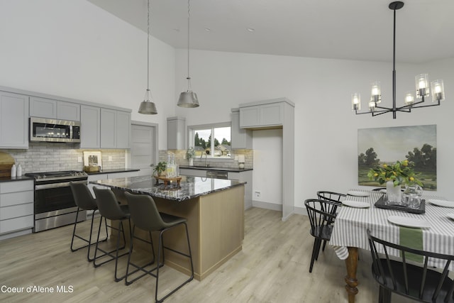 4550 E Savea Ln, Post Falls, ID 83854 - kitchen with appliances with stainless steel finishes, high vaulted ceiling, gray cabinetry, a chandelier, and tasteful backsplash