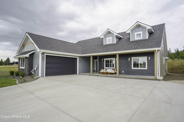4550 E Savea Ln, Post Falls, ID 83854 - view of front of home with a garage, board and batten siding, a shingled roof, concrete driveway, and covered porch
