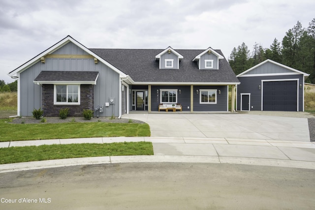 4550 E Savea Ln, Post Falls, ID 83854 - view of front of house with board and batten siding, concrete driveway, a shingled roof, and an outdoor structure