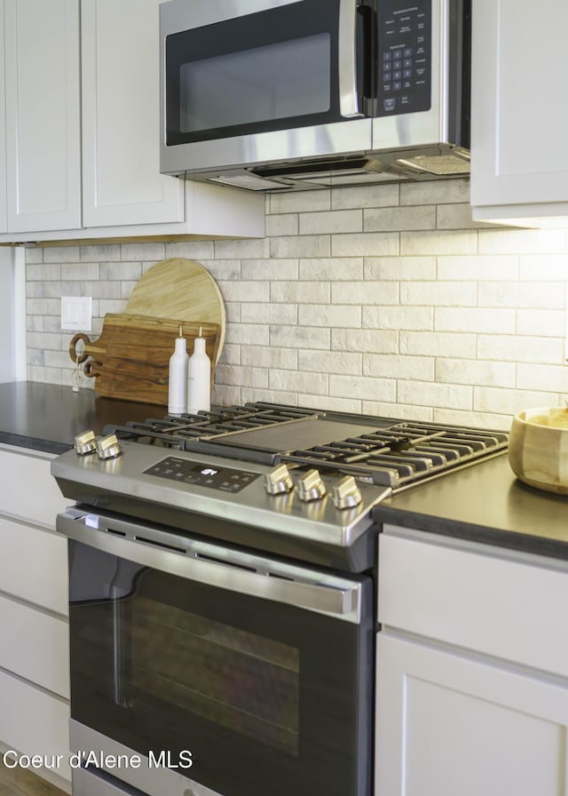 4550 E Savea Ln, Post Falls, ID 83854 - kitchen featuring appliances with stainless steel finishes, backsplash, white cabinets, and dark countertops