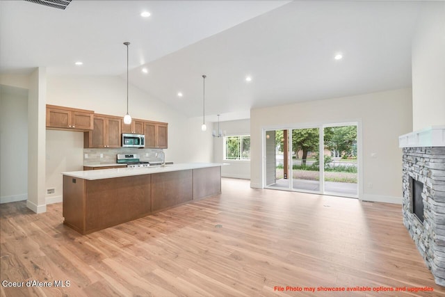 kitchen with appliances with stainless steel finishes, brown cabinets, light countertops, a fireplace, and a sink