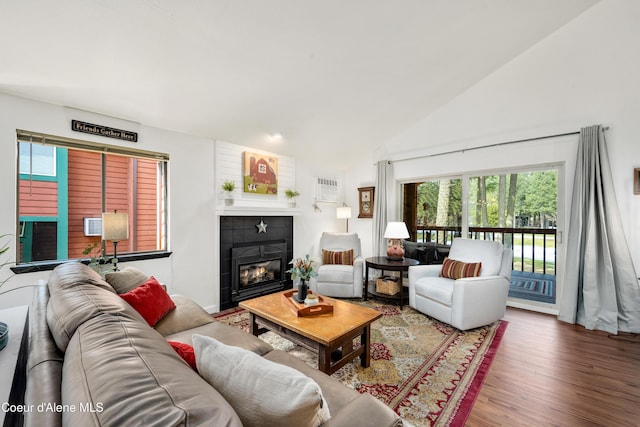 living area with lofted ceiling, a fireplace, and wood finished floors