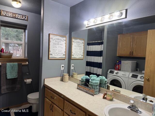 full bath featuring a shower with shower curtain, toilet, vanity, and washing machine and clothes dryer