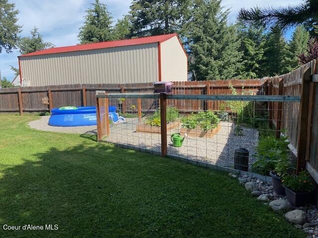 exterior space featuring a garden, a lawn, a fenced backyard, and a swimming pool