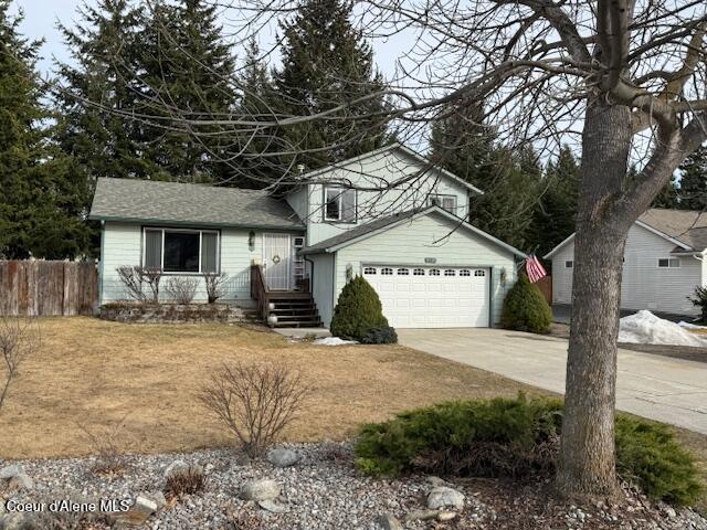 tri-level home with driveway, a garage, and fence