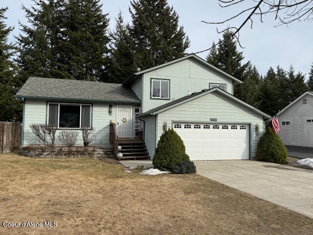 split level home featuring a garage, concrete driveway, and a front lawn