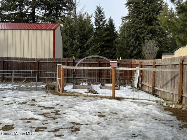 snowy yard with a fenced backyard