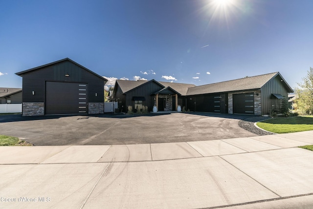 view of front of property featuring a garage, stone siding, aphalt driveway, and board and batten siding