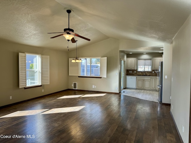 unfurnished living room featuring ceiling fan with notable chandelier, dark wood-style flooring, a sink, visible vents, and vaulted ceiling