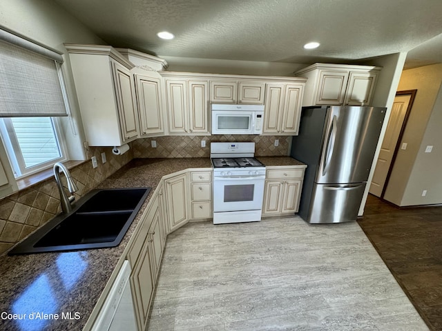 kitchen featuring dark countertops, white appliances, a sink, and light wood finished floors