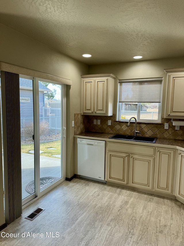 kitchen with cream cabinetry, visible vents, white dishwasher, and a sink