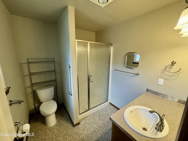 full bathroom featuring toilet, a stall shower, a textured ceiling, and vanity