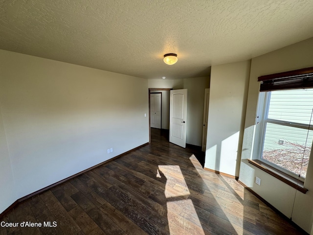 unfurnished bedroom featuring a textured ceiling, dark wood-type flooring, and baseboards