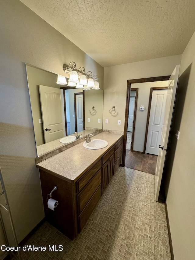 bathroom featuring a textured ceiling, vanity, and baseboards