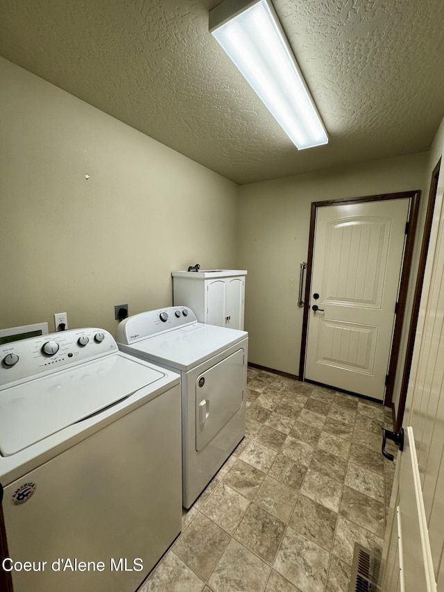 laundry area featuring a textured ceiling, laundry area, washing machine and dryer, and baseboards