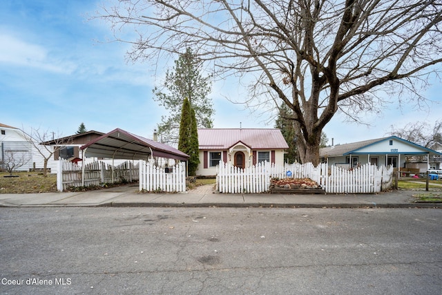 view of front facade with a fenced front yard, a detached carport, metal roof, and driveway