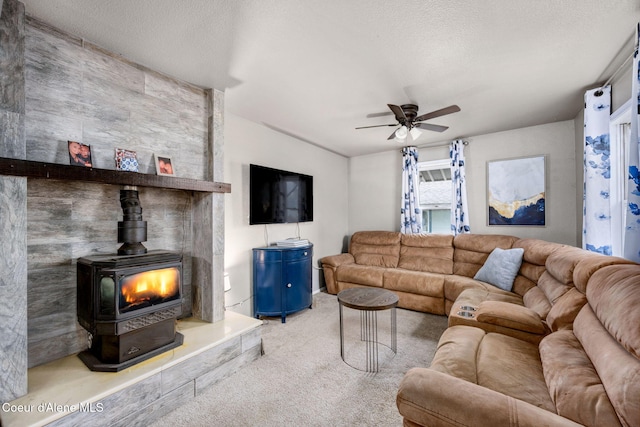 living area with a wood stove, carpet, a textured ceiling, and a ceiling fan