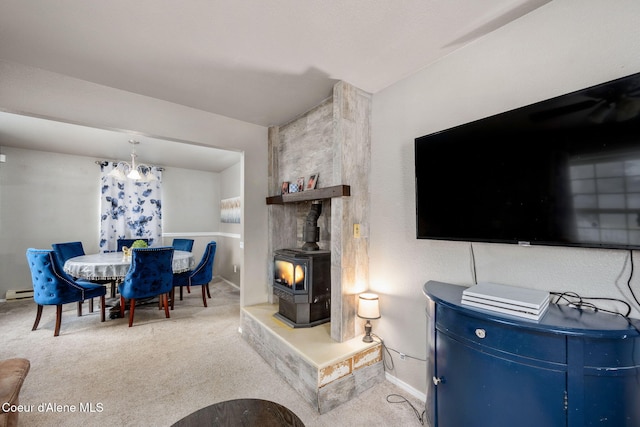 interior space with a baseboard radiator, carpet flooring, baseboards, a wood stove, and an inviting chandelier