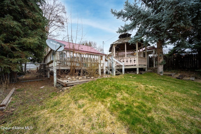 exterior space featuring a yard, metal roof, fence, and a deck