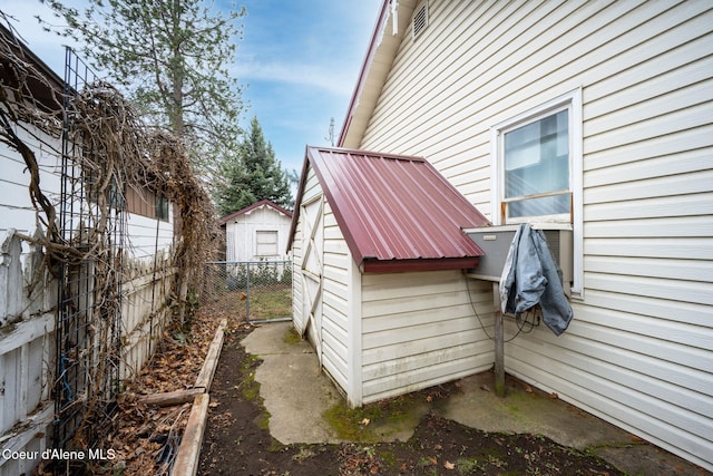 view of side of home featuring metal roof and fence