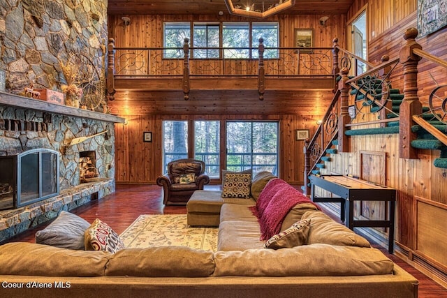 living room featuring plenty of natural light, wooden walls, a fireplace, and wood finished floors