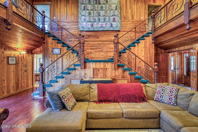 living room with wooden walls, wood finished floors, high vaulted ceiling, wooden ceiling, and stairs