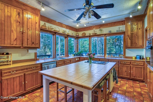 kitchen featuring tile countertops, appliances with stainless steel finishes, and a textured ceiling