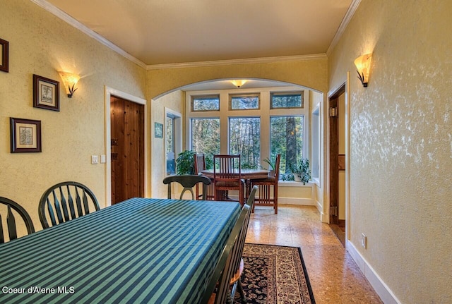 dining space featuring arched walkways, crown molding, and baseboards