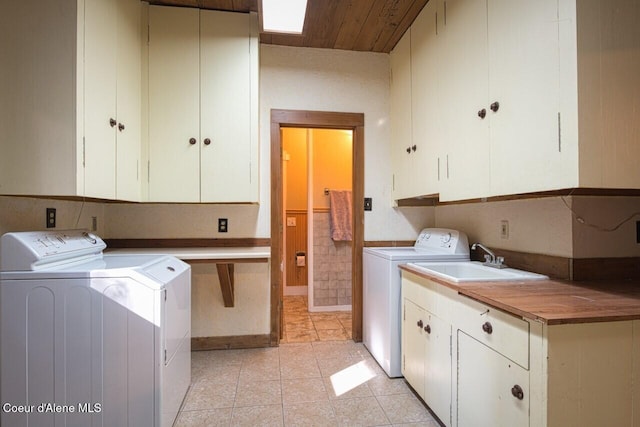 clothes washing area featuring cabinet space, independent washer and dryer, a sink, and light tile patterned floors