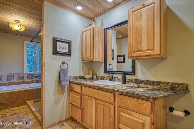 full bathroom with a textured wall, wood ceiling, tiled bath, and vanity