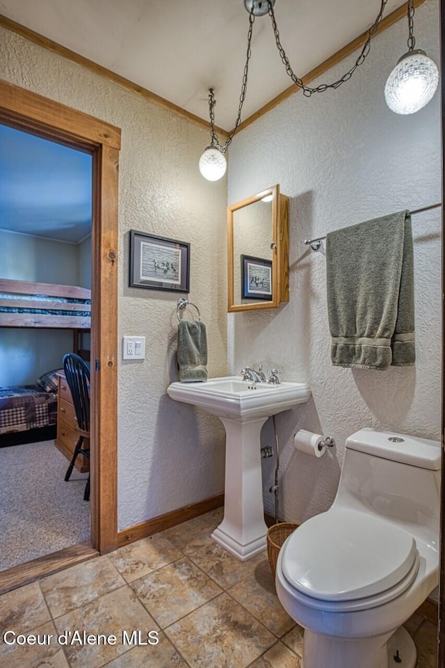 half bathroom featuring toilet, baseboards, crown molding, and a textured wall