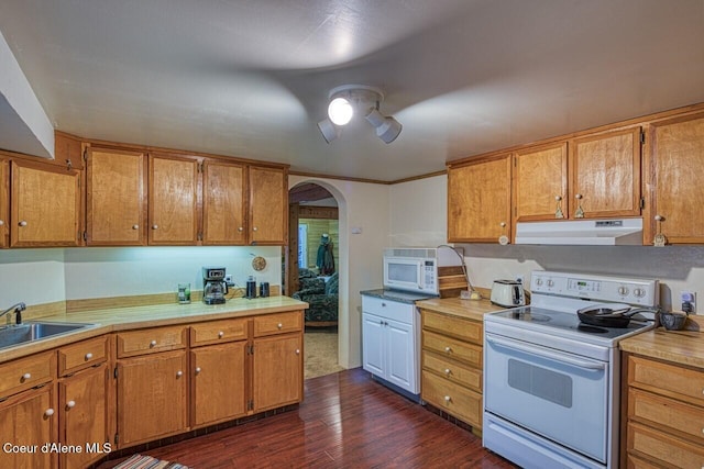 kitchen with white appliances, arched walkways, brown cabinets, under cabinet range hood, and a sink